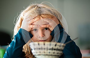 Child have a breakfast. Sad boy eating healthy chicken noodle soup for lunch. Unhappy baby child taking food at home or