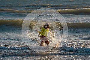 Child have fun on tropical sea beach resort. Funny baby boy run with splashes by water pool along surf edge. Active kids
