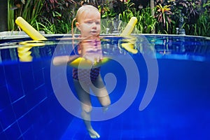 Child have a swimming lesson on polyfoam noodle in pool