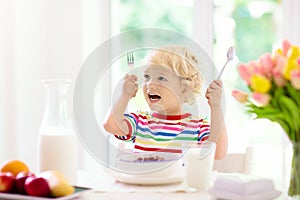 Child eating breakfast. Kid with milk and cereal