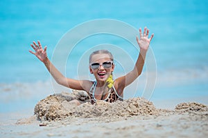 Child having fun at the beach, Cute girl playful in the sunny day, tropical beach.Playing with the sand and waves sea