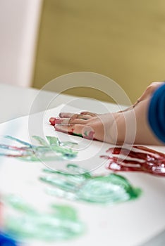 Child having fun with finger paints creating colourful palm prints
