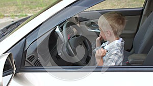 The child is having fun and playing behind the wheel in dad`s car.