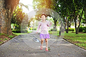 Child having fun playing outside Asian kid girl happy jumping in the park garden tree background - International Childrenâ€™s Day