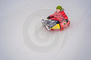 Child having fun on snow tube. Boy is riding a tubing. Winter fun for children
