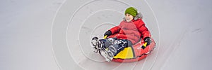 Child having fun on snow tube. Boy is riding a tubing. Winter fun for children BANNER, LONG FORMAT