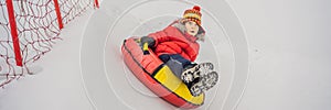 Child having fun on snow tube. Boy is riding a tubing. Winter fun for children BANNER, LONG FORMAT