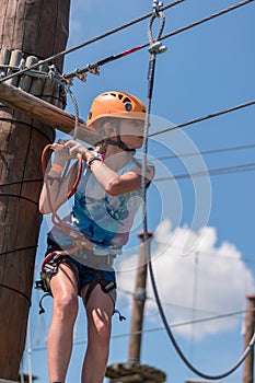 Child having fun on wooden rope slide in climbing centre