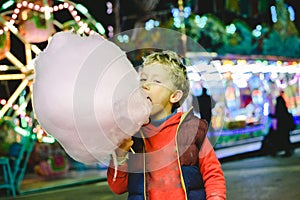 Child having a great time eating a candy floss at a night fair