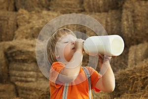 Child on a haystack drink milk