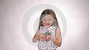Child with headphones dancing at studio background. Girl listens to music on smartphone. Beautiful cute happy little