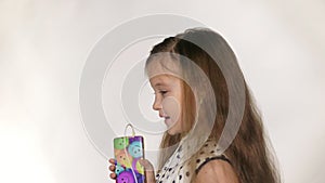 Child with headphones dancing at studio background. Girl listens to music on smartphone. Beautiful cute happy little