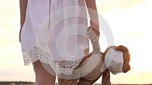 Child health concept. child holds his beloved teddy bear in a protective mask during quarantine. girl carries in her