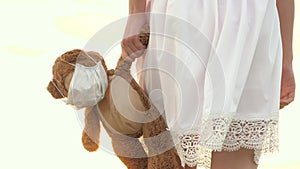 child health concept. child holds his beloved teddy bear in a protective mask during quarantine. girl carries in her