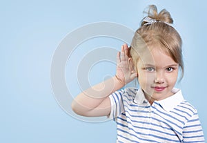 Child with hearing problem on blue background empty copy space. Hearing loss, symptoms and treatment concept