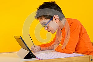 Child hears a remote lesson with the school teacher due to covid-19 pandemic. yellow background