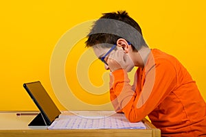 Child hears a remote lesson with the school teacher. yellow background