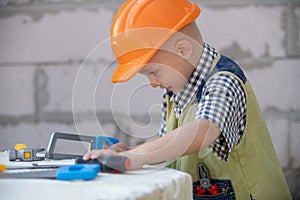 Child in helmet is construction worker. Foreman kid work in the hard hat making repairs. Childhood development. Little