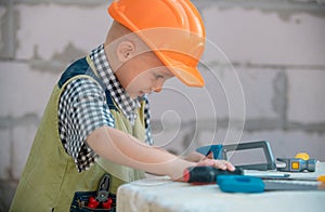 Child in helmet is construction worker. Foreman kid work in the hard hat making repairs. Childhood development. Little