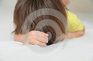 Child hiding face lying on bed, crying offended little girl