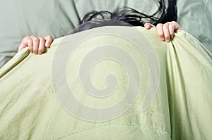 Child hiding her face with a blanket.