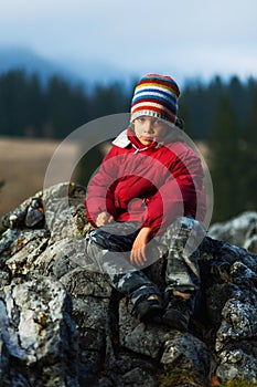 Child hiker sitting on cliff