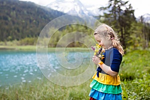Child hiking in flower field at mountain lake