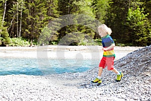 Child hiking in mountains. Kids at river shore