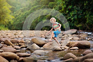 Child hiking in mountains. Kids at river shore