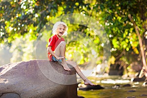 Child hiking in mountains. Kids at river shore