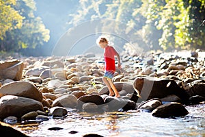 Child hiking in mountains. Kids at river shore