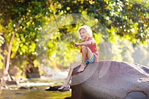 Child hiking in mountains. Kids at river shore