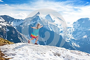 Child hiking in mountains. Kids in snow in spring.