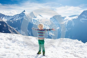 Child hiking in mountains. Kids in snow in spring.