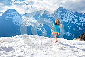 Child hiking in mountains. Kids in snow in spring