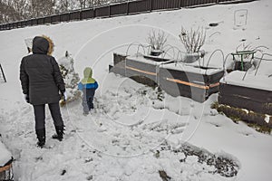 Child with his mother plays in winter garden.