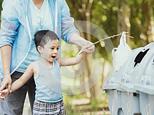 Child and his mother in teaching to drop things on trash in park