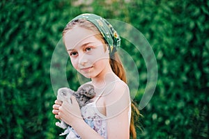 Child holding baby cat. Kids and pets. Little girl hugging cute little kitten in summer garden.Domestic animal in family