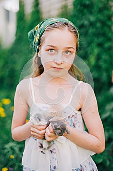 Child holding baby cat. Kids and pets. Little girl hugging cute little kitten in summer garden.Domestic animal in family