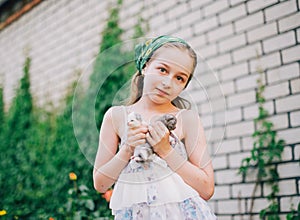 Child holding baby cat. Kids and pets. Little girl hugging cute little kitten in summer garden.Domestic animal in family