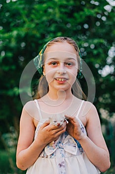 Child holding baby cat. Kids and pets. Little girl hugging cute little kitten in summer garden.Domestic animal in family