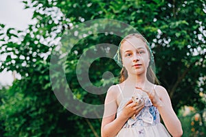 Child holding baby cat. Kids and pets. Little girl hugging cute little kitten in summer garden.Domestic animal in family