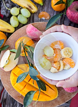 Child holding a bowl of fruit