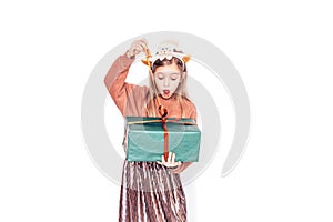 Child holding a box in green packaging with a gift. Christmas mood. She has antlers on her head