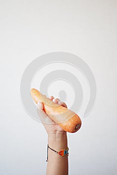 A child is holding a carrot as a food ingredient in their hand