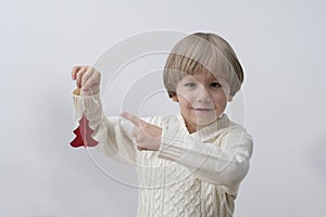 Child holding Christmas decoration in hand. Boy on white background. New year and x-mas concept.