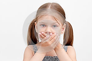 Child holding crossed hands on mouth photo