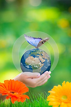 Child holding Earth planet with blue butterfly in hands