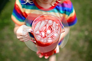 Child Holding Freshly Made Pitcher of  Red Summer Drink with Ice