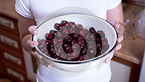 Child Holding Full Bowl Red Cherries in Hands While Standing in Kitchen. 4K